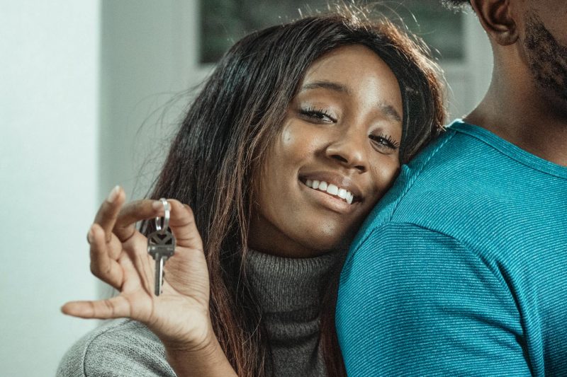 Joyful couple celebrating their new home, holding a set of house keys together.