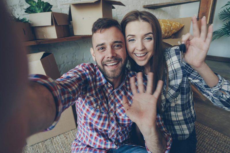 Cheerful couple celebrating in their new home, surrounded by unpacked boxes and smiles.