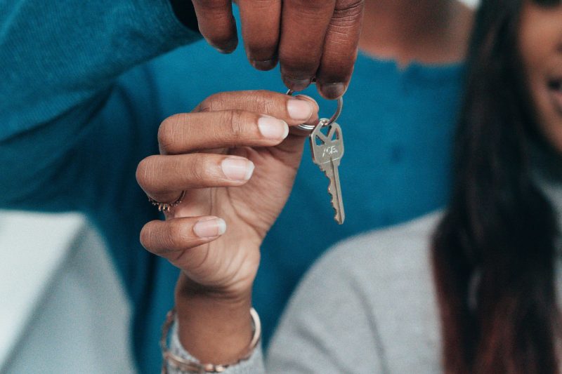 A couple joyfully holding a house key together, symbolizing new homeownership.