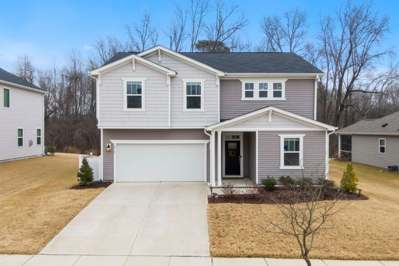 Charming two-story suburban home with a garage surrounded by greenery in Fuquay-Varina, NC.