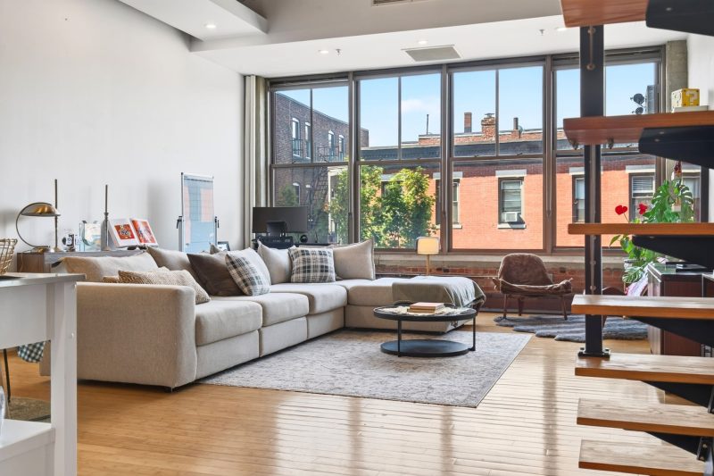 Bright industrial-style loft in Boston featuring large windows, modern furnishings, and an open layout.