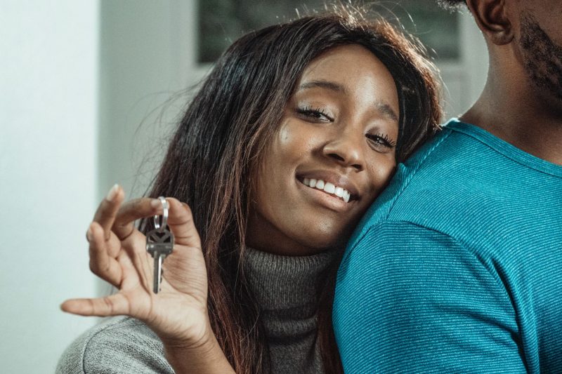 Joyful couple holding house keys, celebrating their new home purchase.