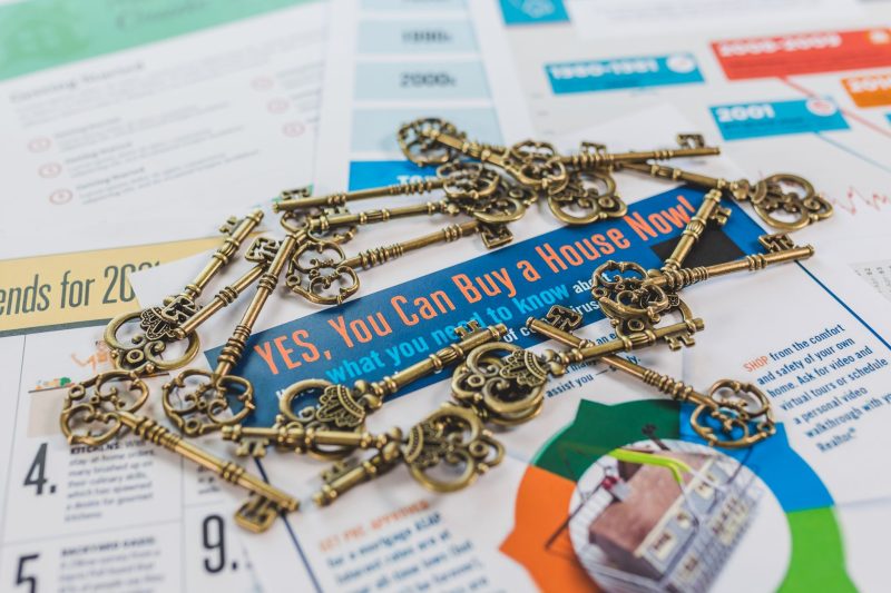 Vintage keys arranged on a real estate brochure, highlighting house buying options.
