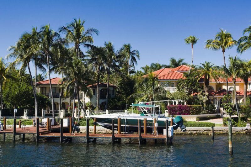 Luxury waterfront homes, palm trees, and a boat docked in Fort Lauderdale, Florida.