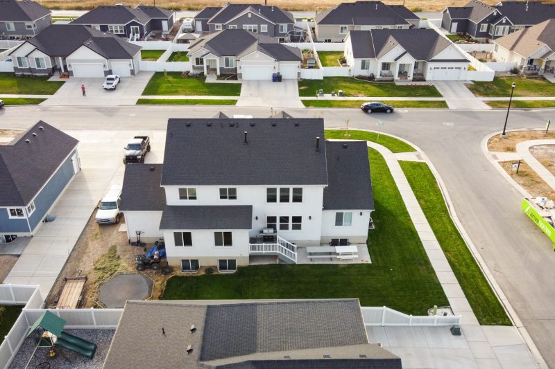 Aerial view of modern homes with manicured lawns in a suburban neighborhood in Spanish Fork, Utah.