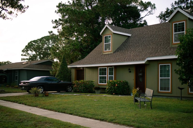A charming suburban home with a manicured lawn and a parked car, reflecting residential comfort.