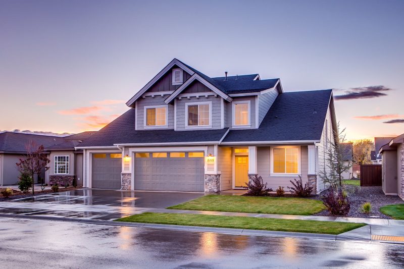 Elegant suburban home with modern architecture and a driveway, illuminated by warm sunset light.